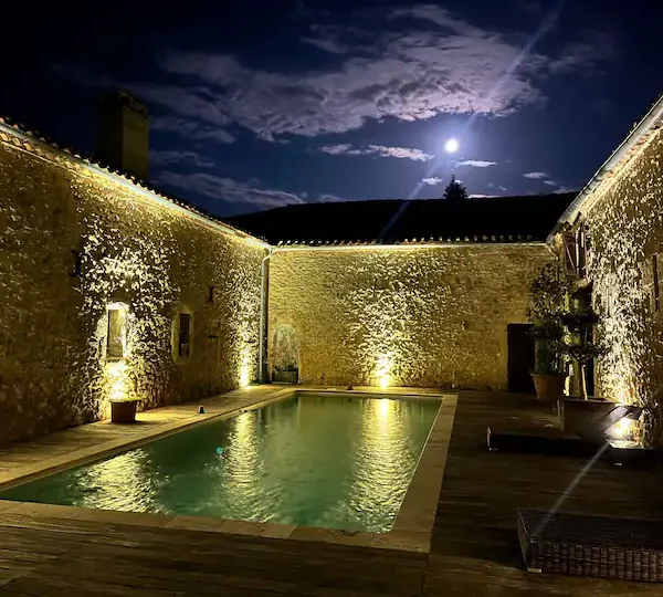 Vu de nuit avec la pleine lune du patio et de la piscine du domaine de pourrouquet